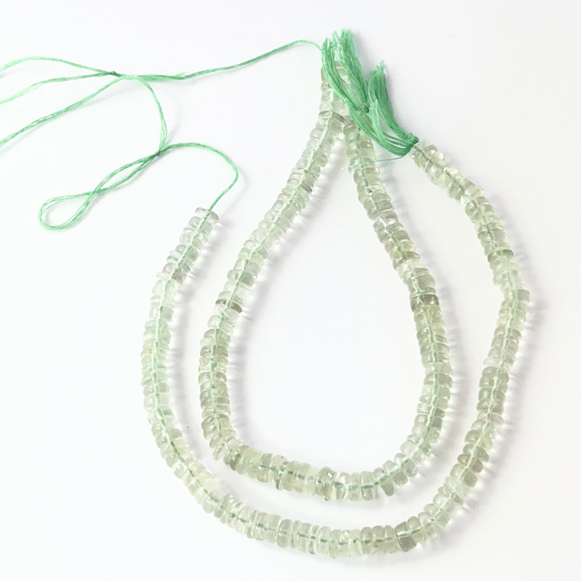 Close-up of polished green amethyst wheel beads, 5.5–6.0mm, strung on a 21cm strand.