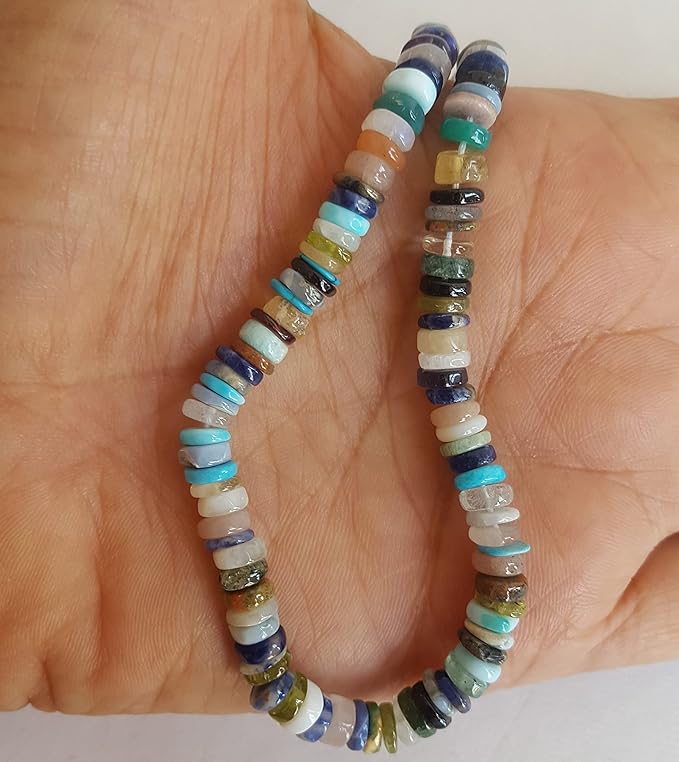 A person holds a strand made of Heishi smooth wheel beads featuring vibrant multi-coloured gemstones. 