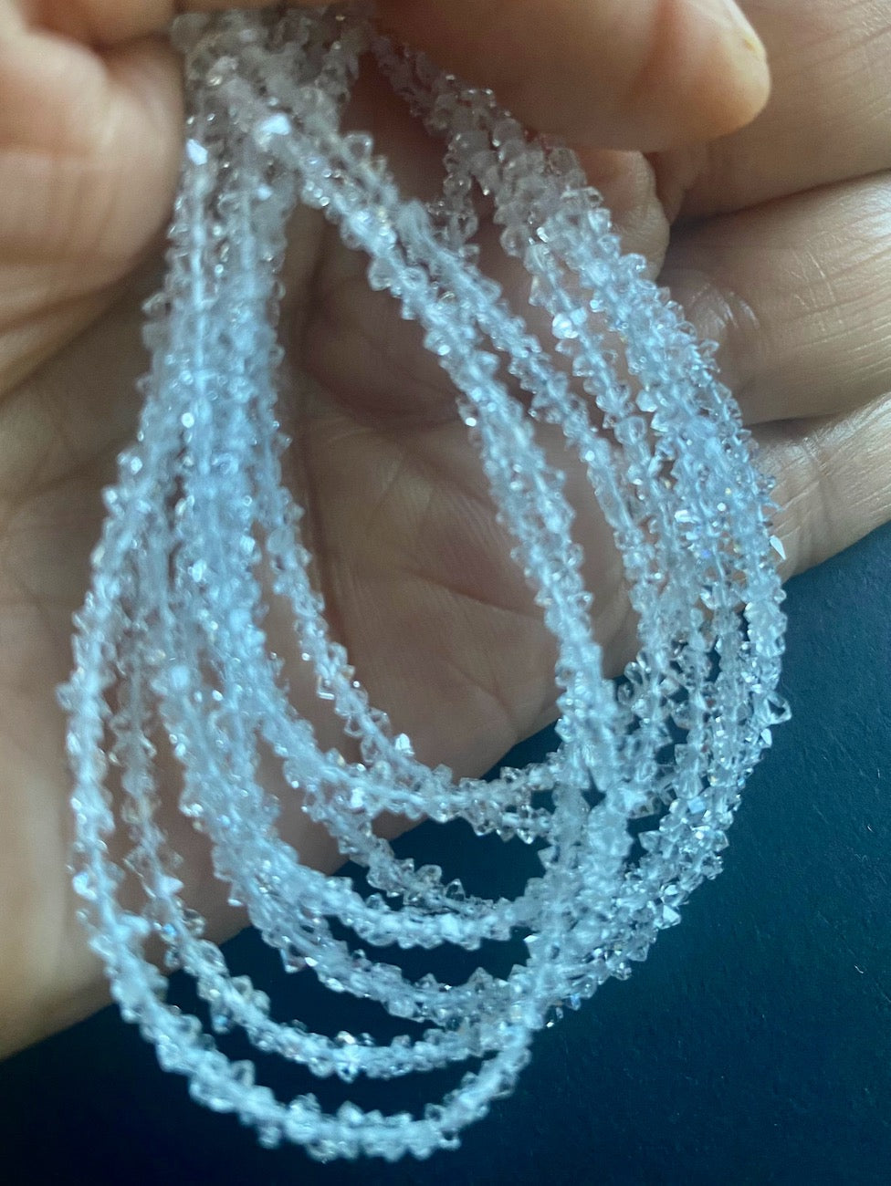 
A hand holding a cluster of Herkimer, showcasing its natural rough texture and sparkling facets.
