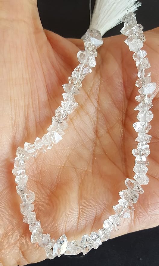 Elegant strand of clear Herkimer Diamond beads, adorned with a silver tassel placed in a person's hand