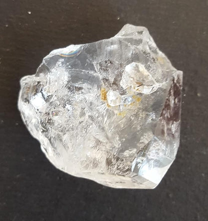 A rough Herkimer diamond gemstone displayed on a table, highlighting its unique shape and brilliant clarity.