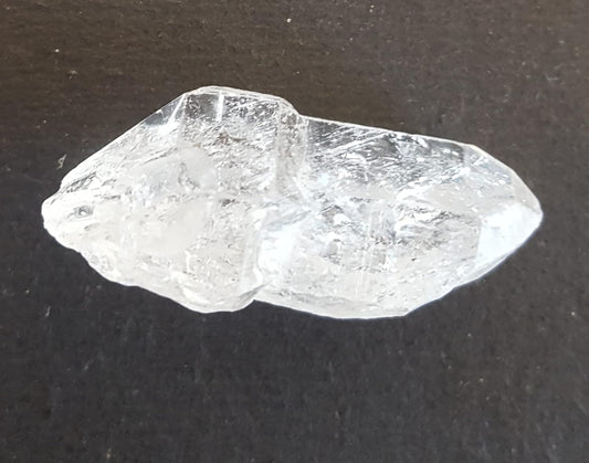  A Herkimer diamond gemstone resting on a table, showcasing its natural rough texture and sparkling facets.
