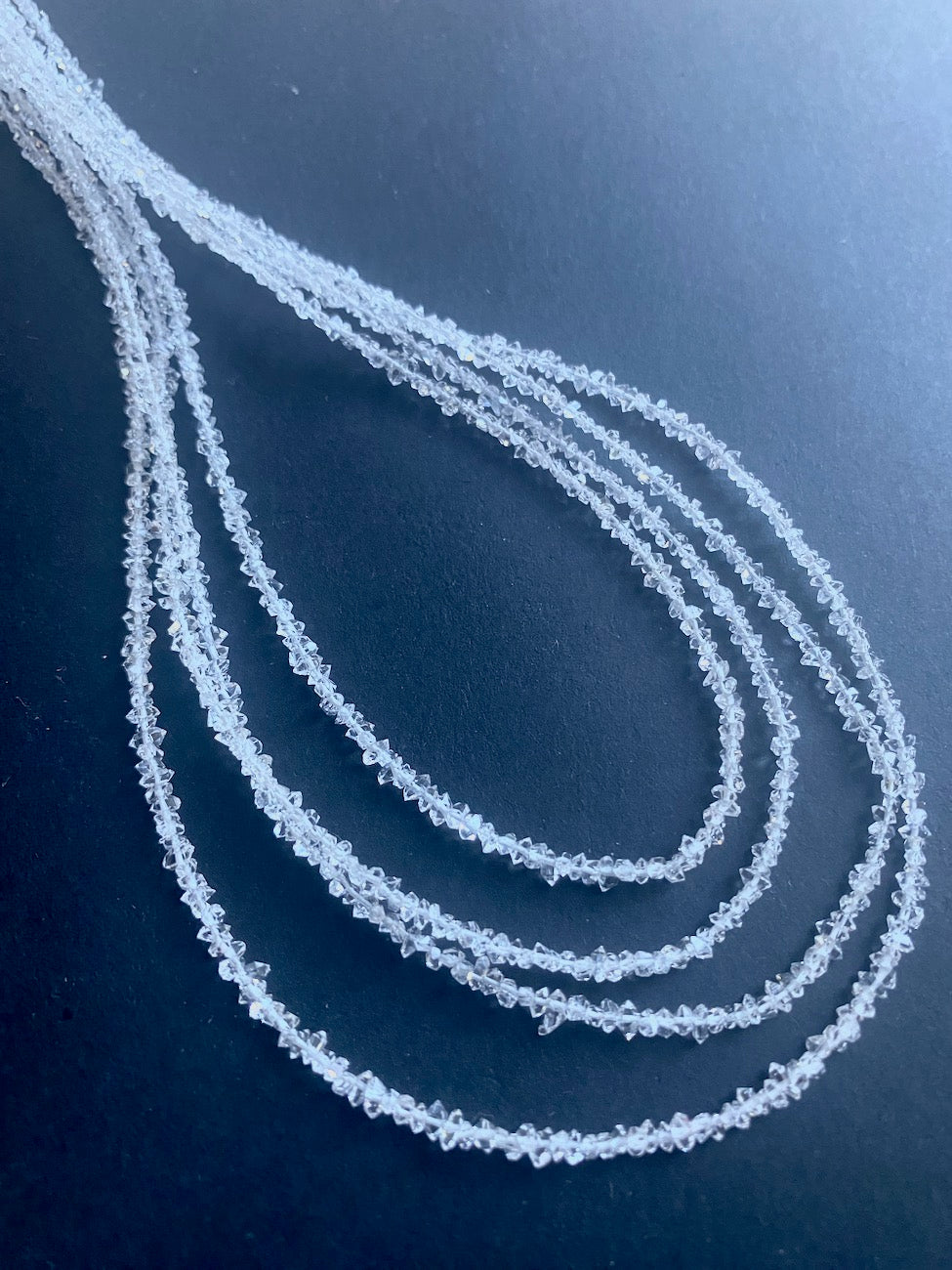  A Herkimer diamond stone beads on a table, featuring its striking clarity, capturing light beautifully.