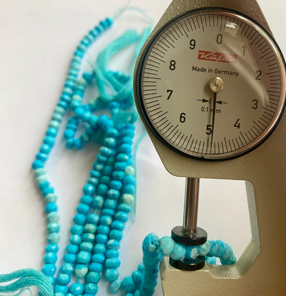 A dial gauge measures the howlite turquoise faceted rondelle gemstone.