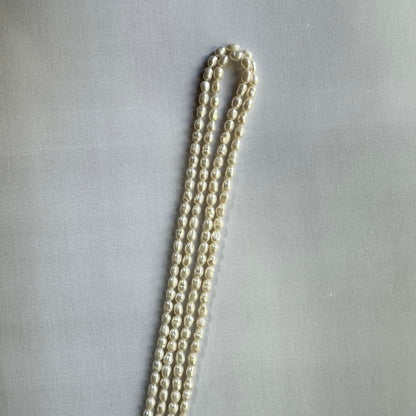 Loose freshwater pearl smooth rice beads spread out, revealing their consistent sizing and high-quality craftsmanship.
