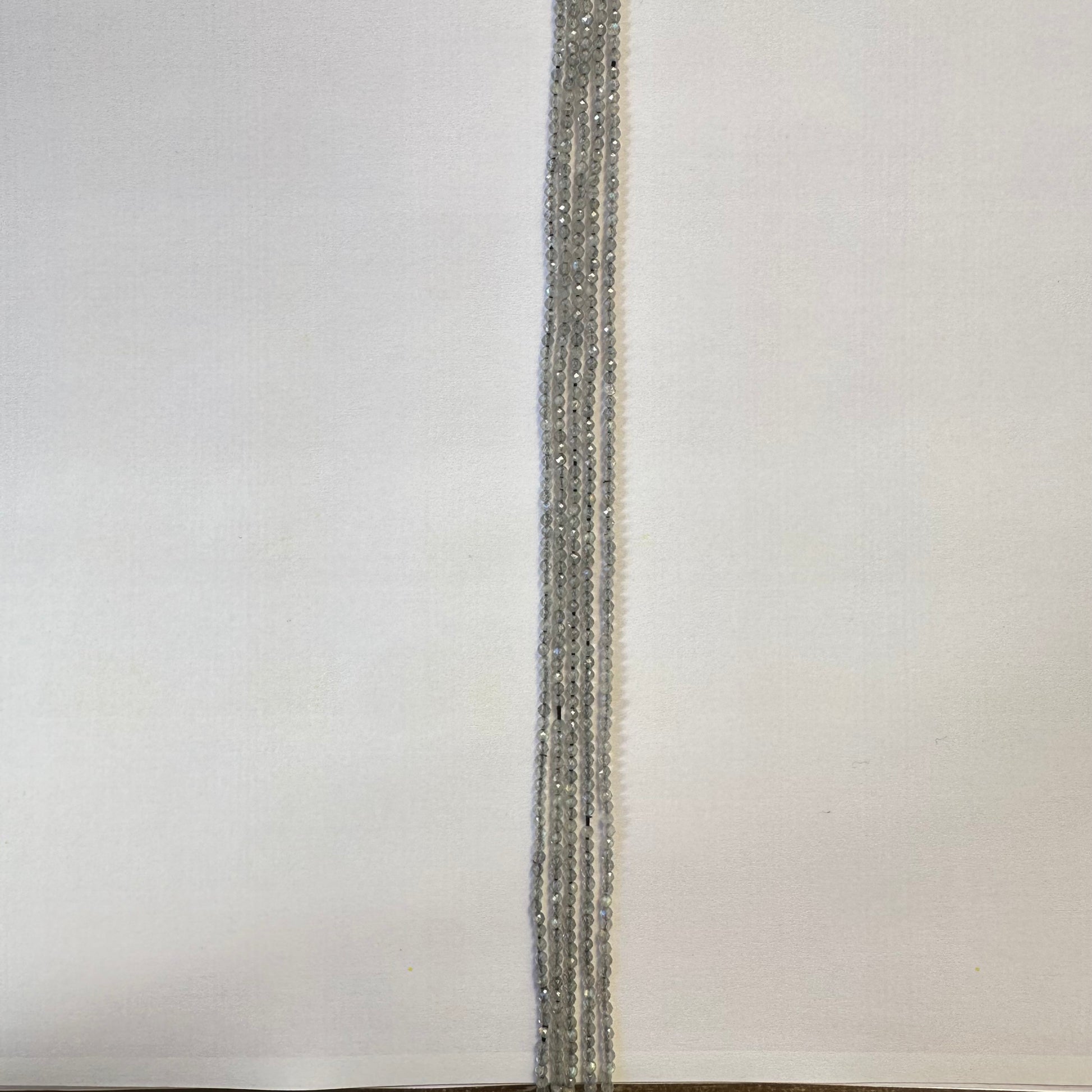 A jewellery artist arranges Labradorite beads, creating a refined gemstone piece with balanced proportions.