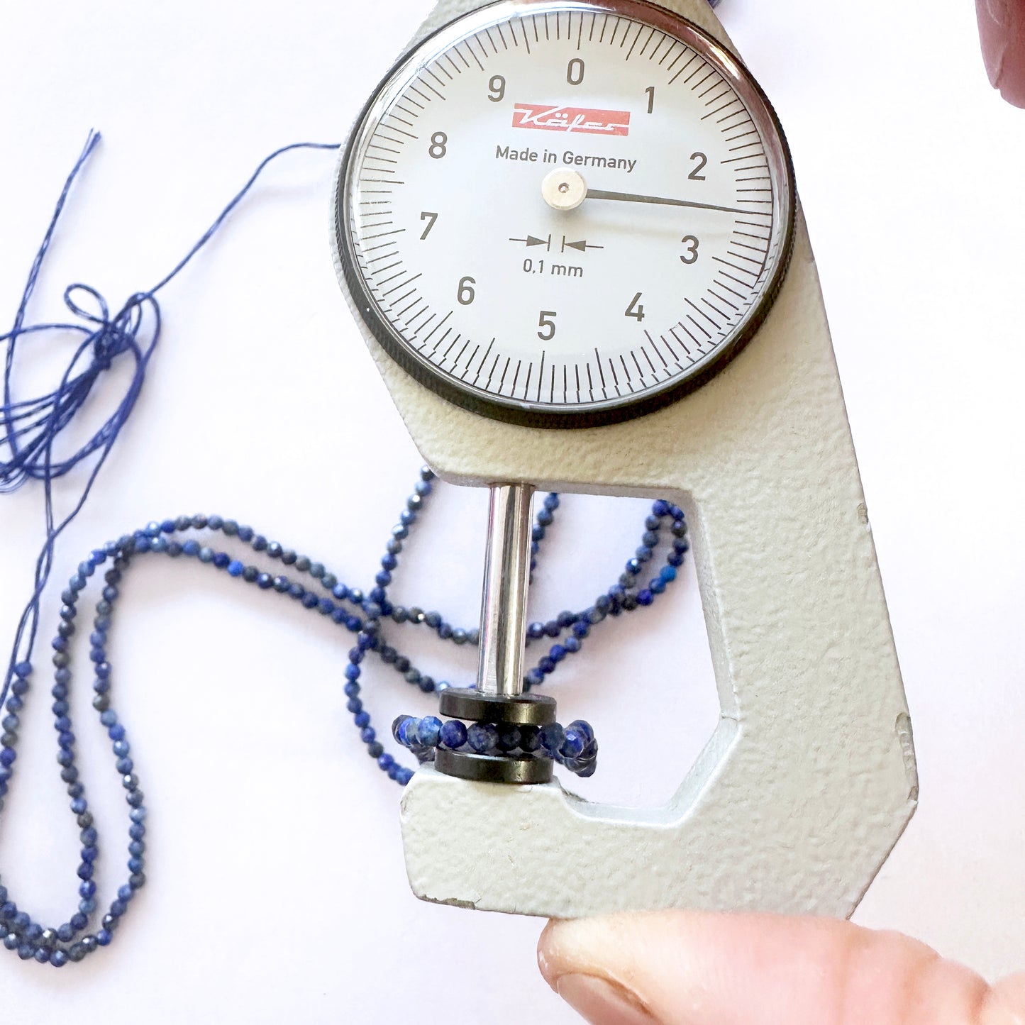 A dial gauge measures the Lapis Lazuli faceted rondelle 2.5mm gemstone for quality assurance.