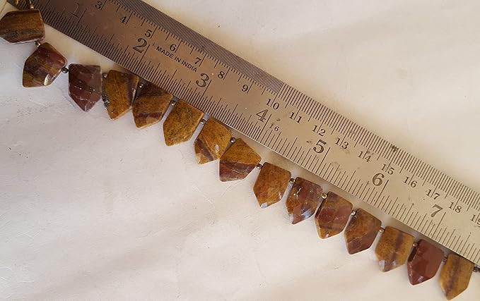 A ruler placed next to a group of Jasper beads, each measuring between 11mm and 17mm.