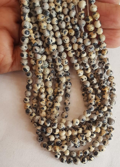 Close-up of a bead strand with 4mm to 4.5mm smooth round beads, showcasing a striking black and white spotted design.