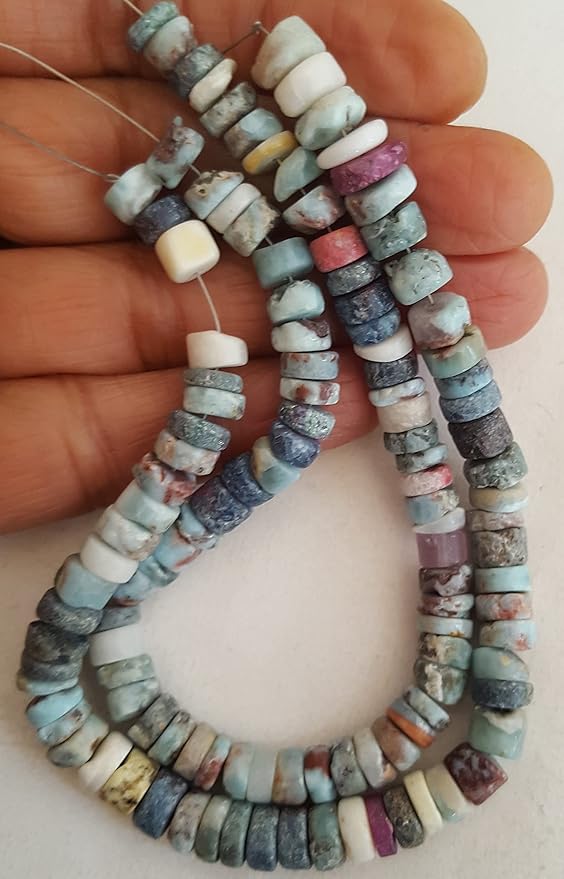 A hand holding a cluster of Larimar gemstone beads, showcasing their texture and vibrant colour.