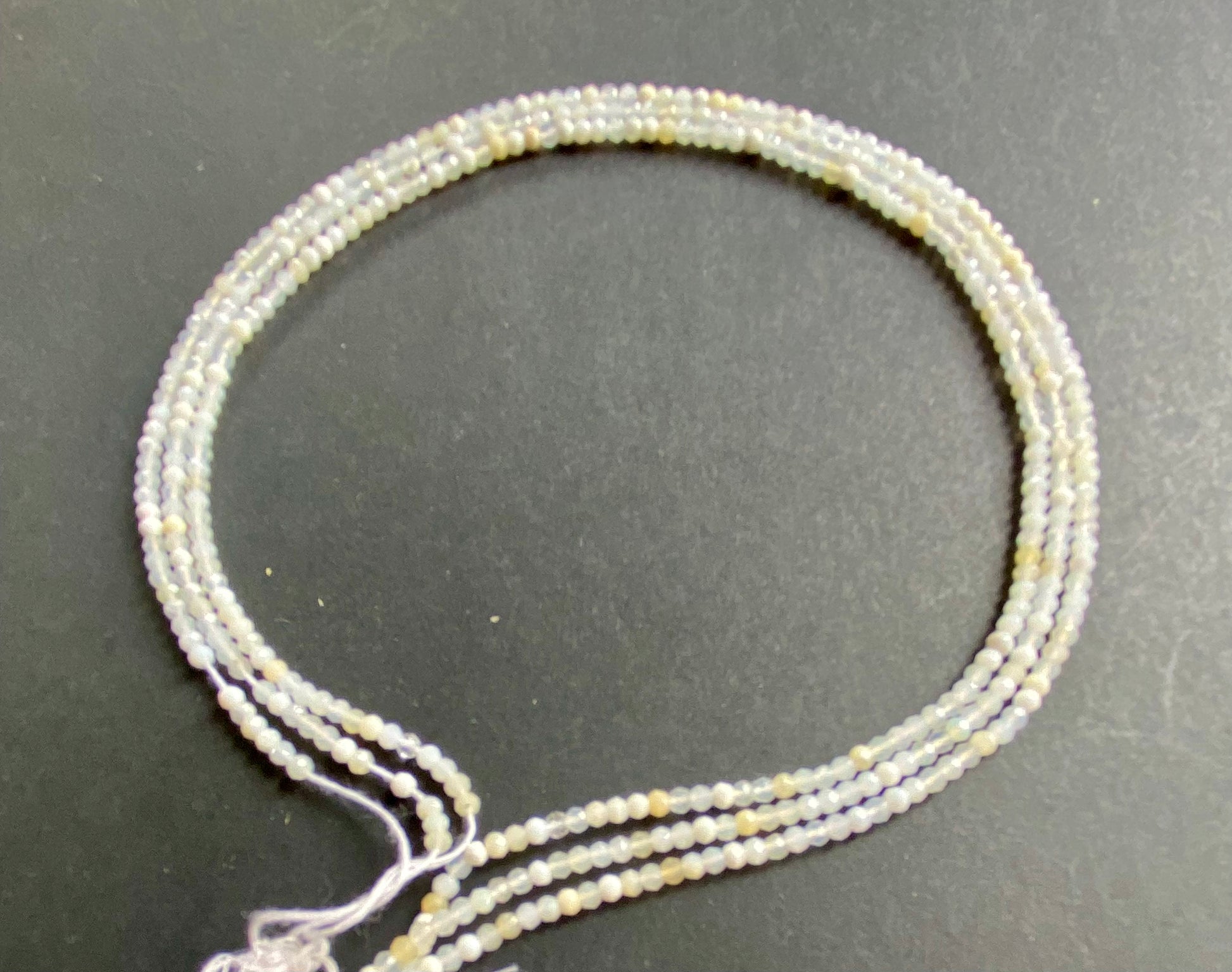 A close-up of a multiple strands  featuring micro-faceted opal rondelle beads, measuring 2.6-2.7mm in size.