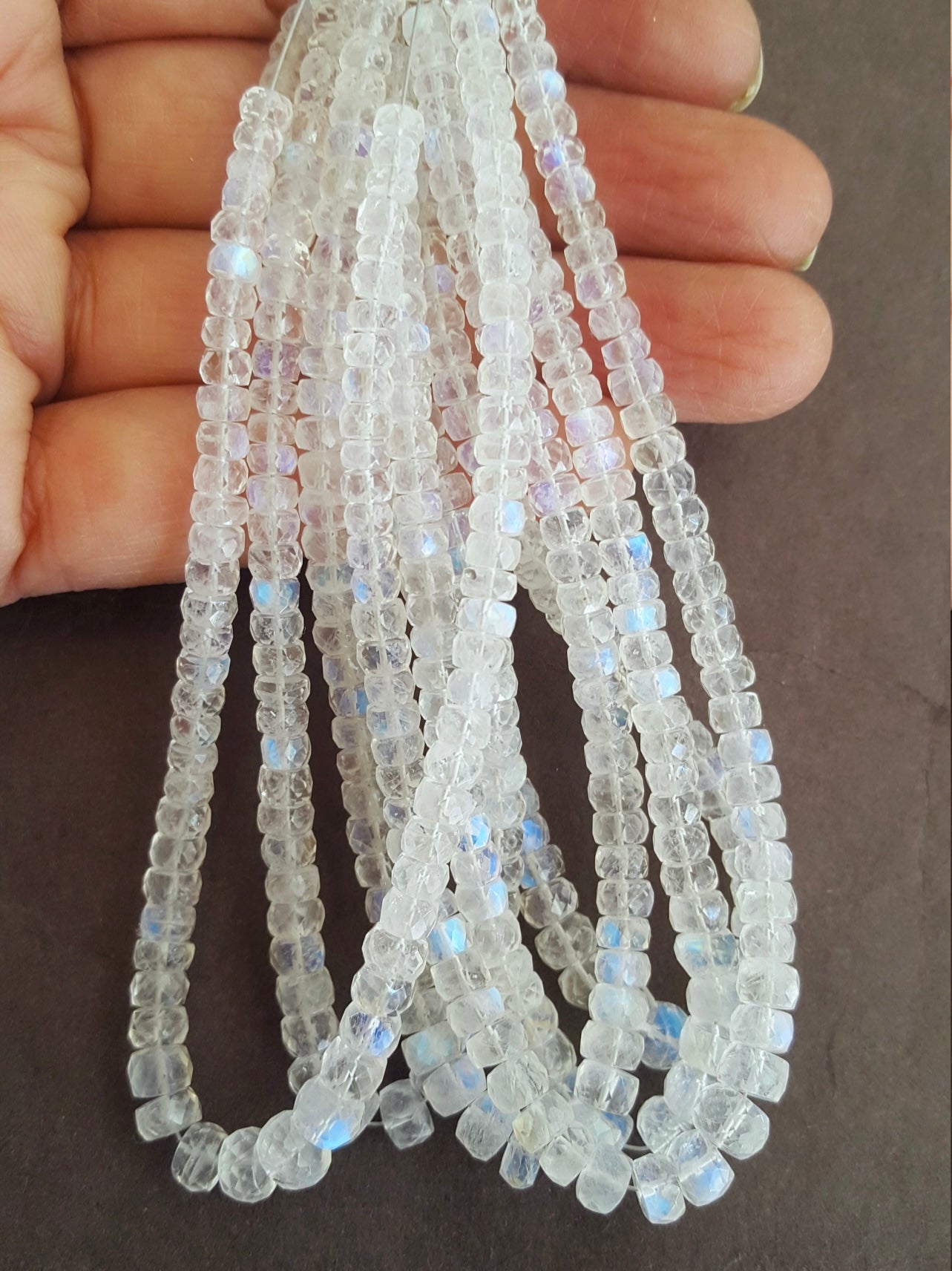 A person holding a vibrant bunch of Moonstone beads in fascinating colours.