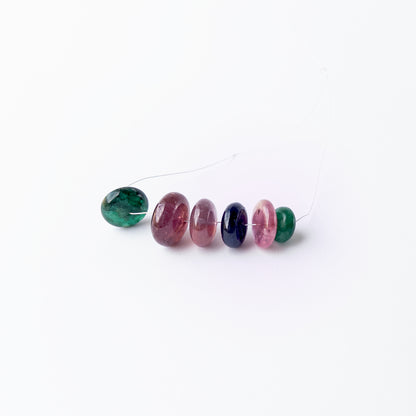 Multi‑precious Emerald, Ruby and Blue Sapphire smooth rondelle beads arranged together, showcasing rich colour and polished shine.