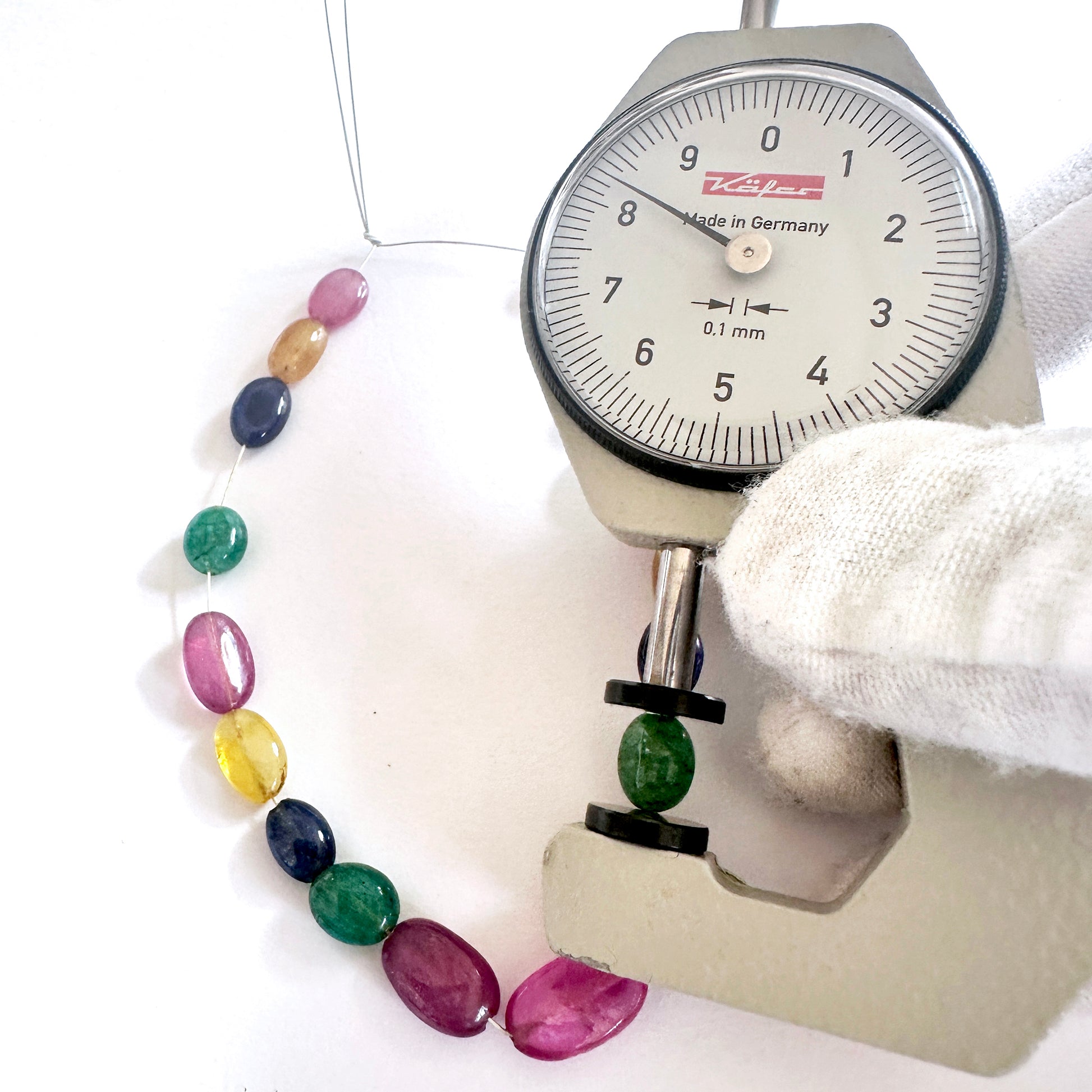 A dial gauge measures the blue sapphire smooth oval gemstone for precision and quality.