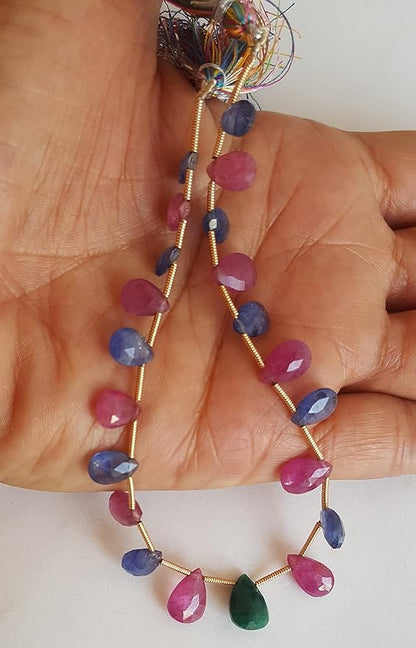 A hand displays a colourful assortment of faceted beads, featuring ruby, blue sapphire, and emerald.