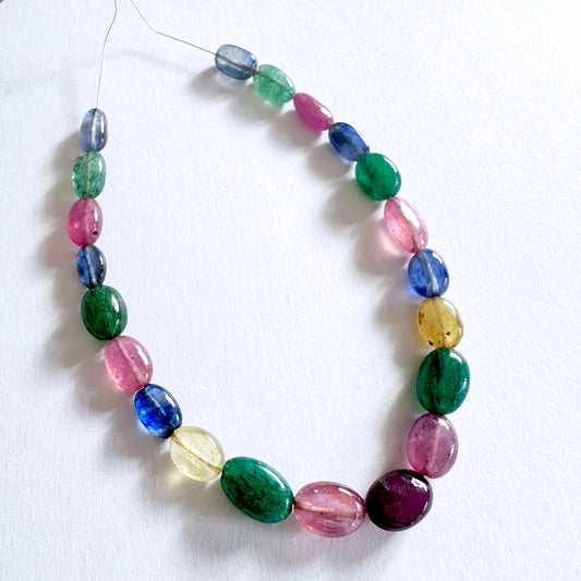 Smooth oval multi stone beads featuring ruby, sapphire, and emerald in vibrant hues across 21 polished pieces.