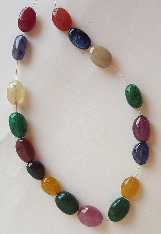 A colourful strand made of smooth oval, precious natural beads in ruby, blue sapphire, yellow sapphire, and emerald against a white backdrop.