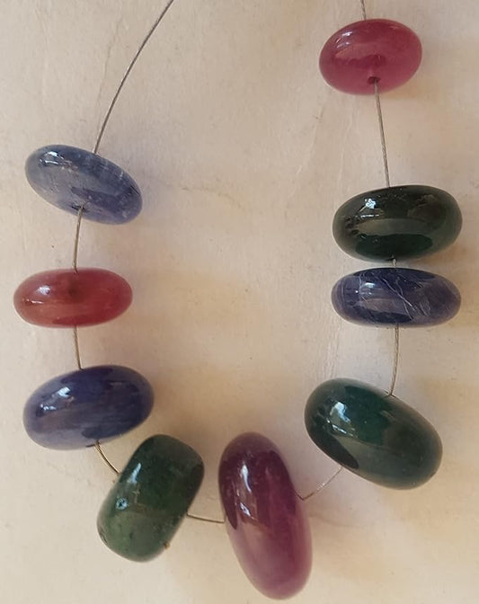 A colourful strand made of smooth rondelle beads in ruby, blue sapphire, and emerald against a white backdrop.