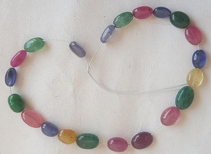  A vibrant multi-coloured strand featuring ruby, blue sapphire, yellow sapphire, and emerald beads on a white background.