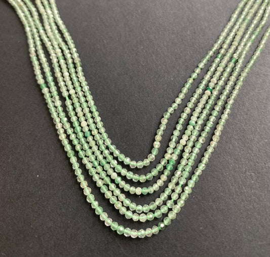  A striking strands with green Amethyst beads resting on a black surface, showcasing the vivid colours and elegant design.
