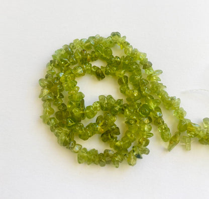 Vibrant Peridot chip beads 5 to 8mm with a polished finish arranged in a 45cm strand for jewellery making.