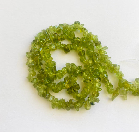 Vibrant Peridot chip beads 5 to 8mm with a polished finish arranged in a 45cm strand for jewellery making.