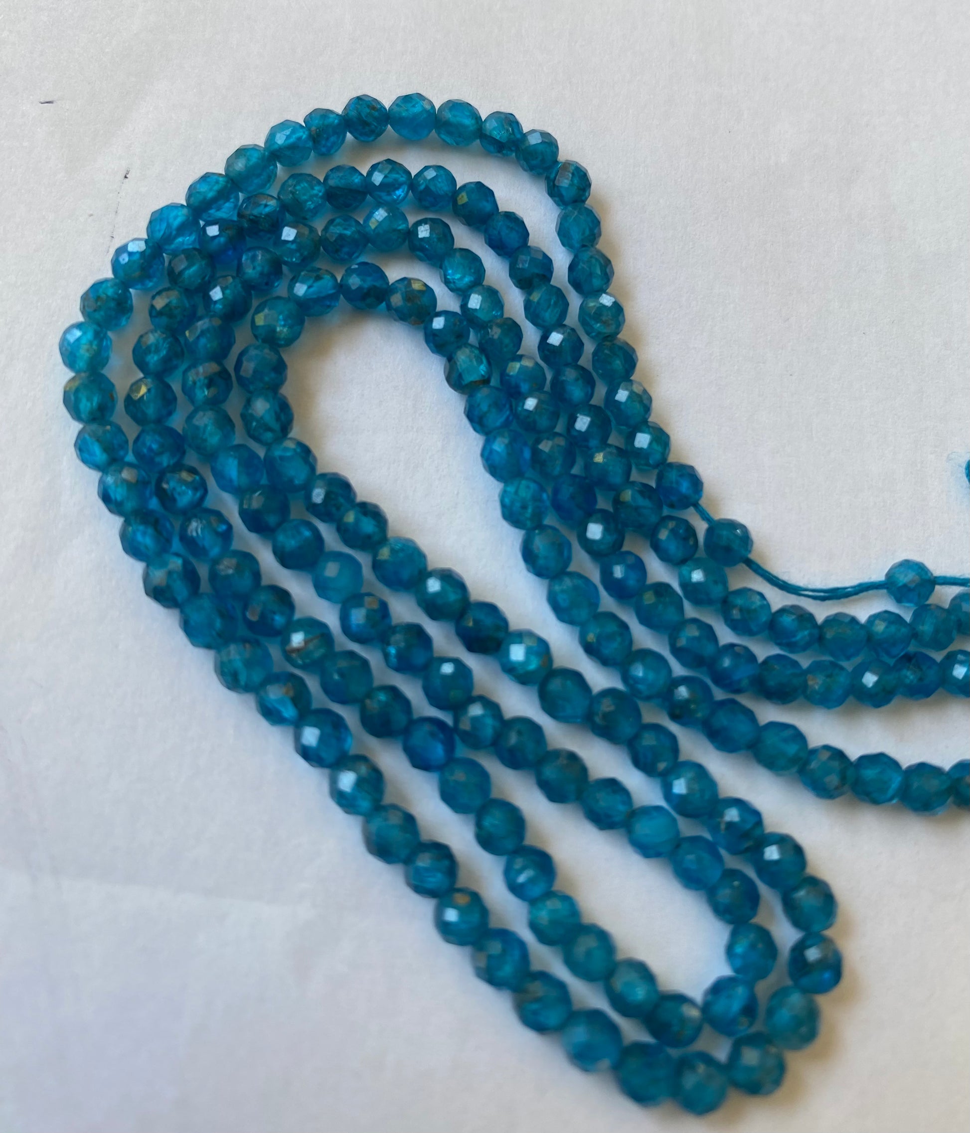 A blue gemstone bead strand showcasing neon apatite faceted rondelle gemstones.