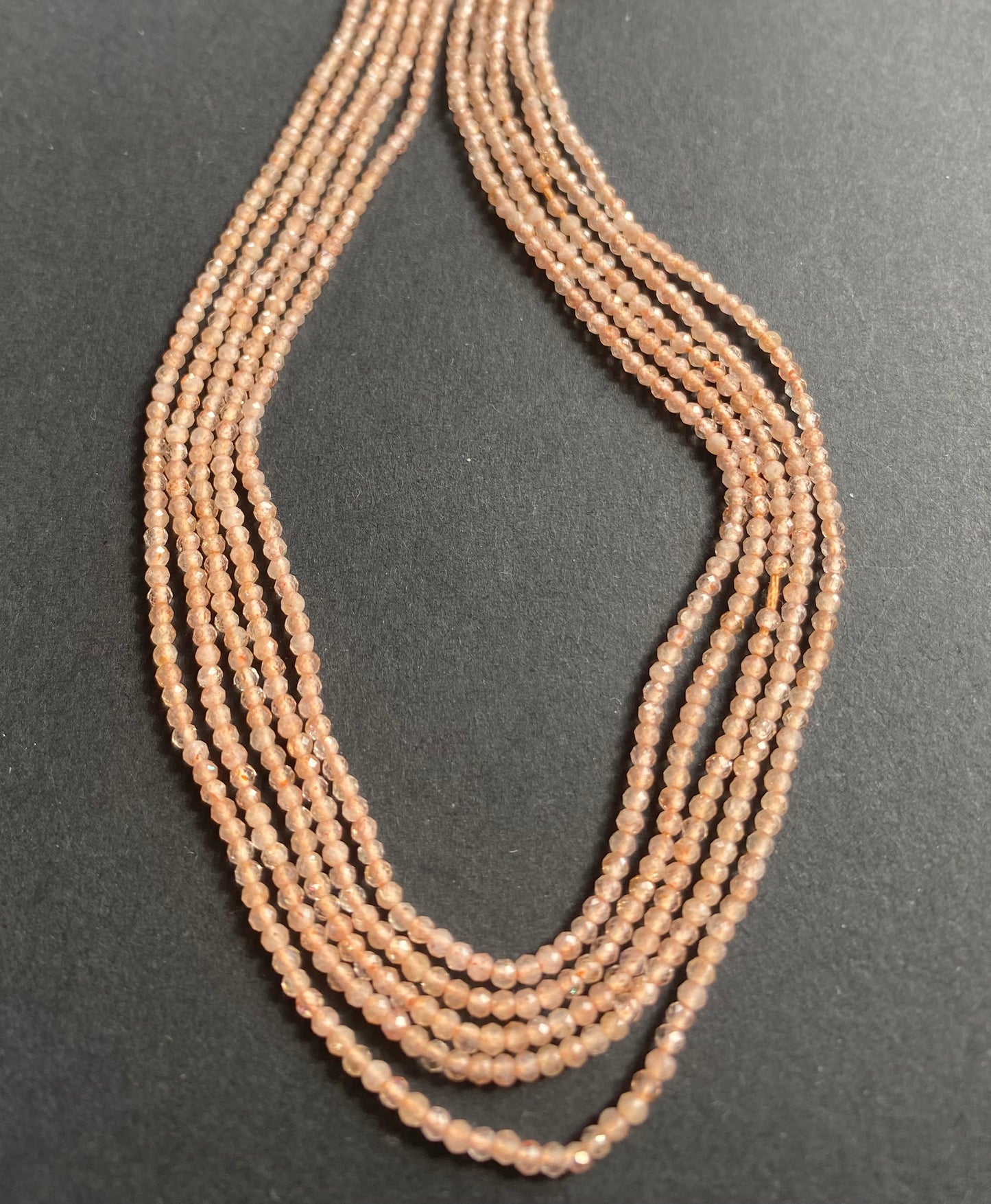 Delicate peach moonstone rondelle beads glimmer on a sleek black background, highlighting their soft, warm hue.