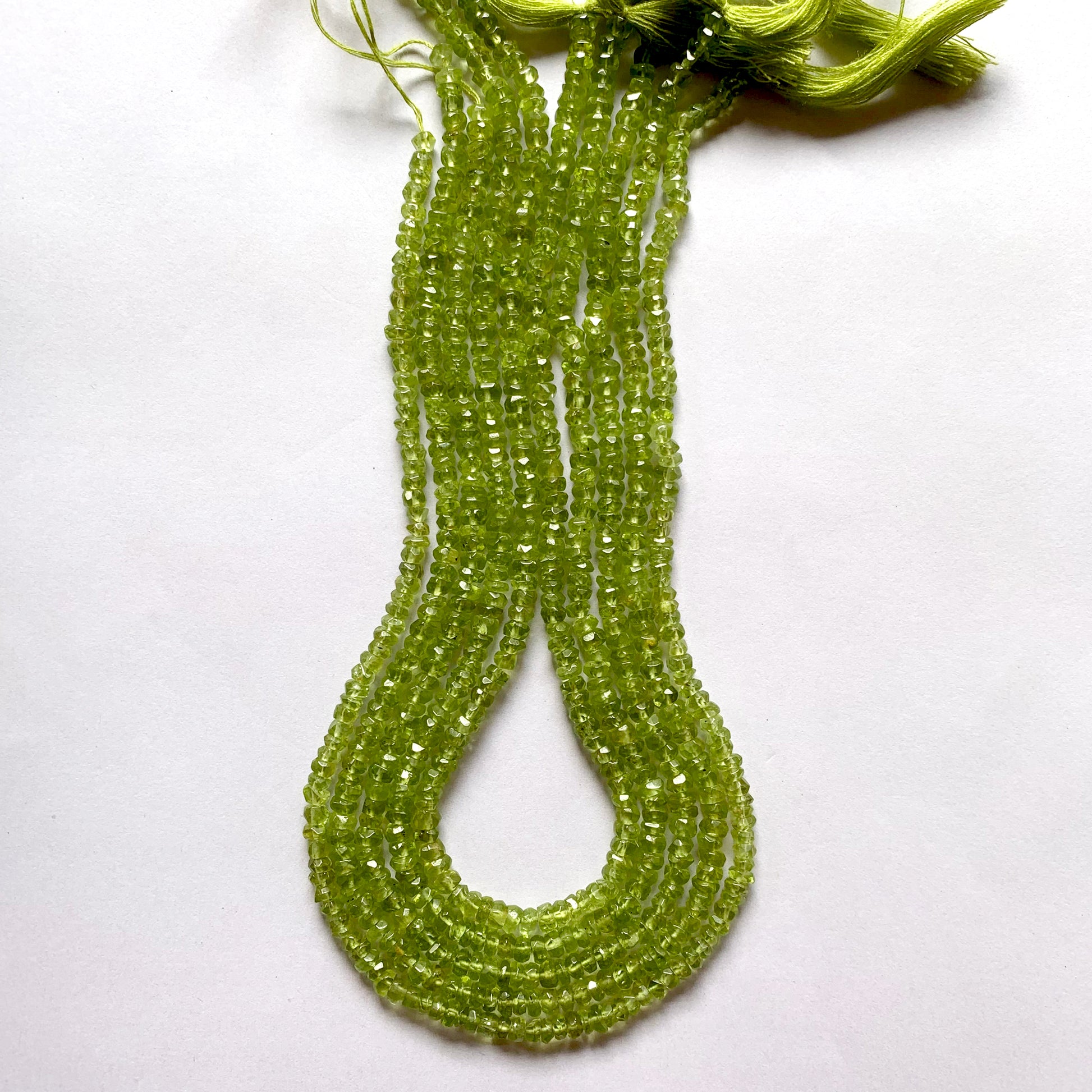 Strand featuring faceted rondelle peridot gemstones, ranging from 3.7mm to 4.4mm, in a stunning green hue.