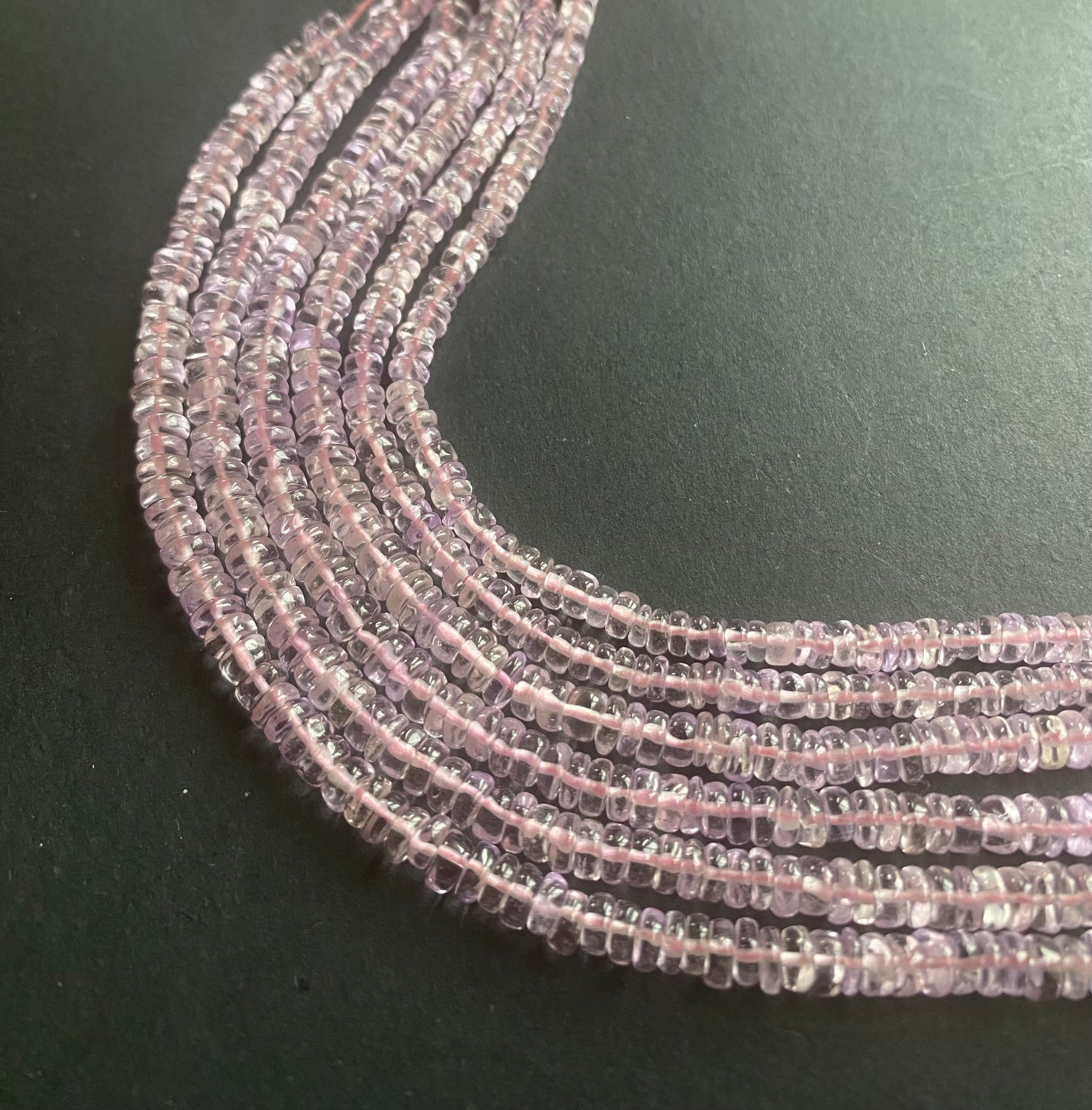  A vibrant pink amethyst strand on a dark contrast background.