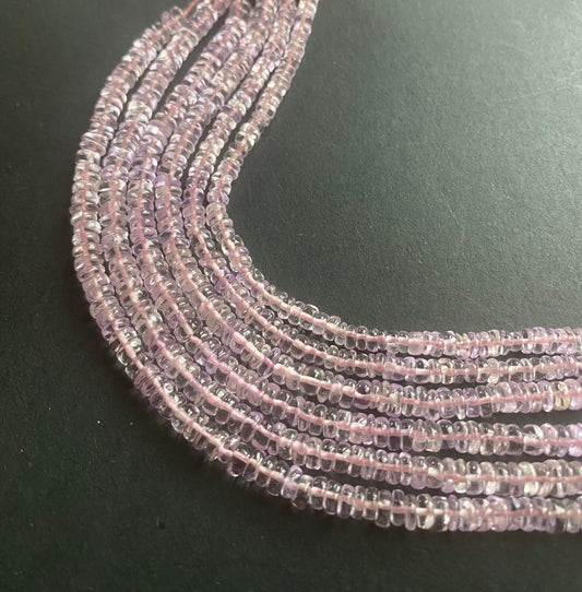  A vibrant pink amethyst strand on a dark contrast background.