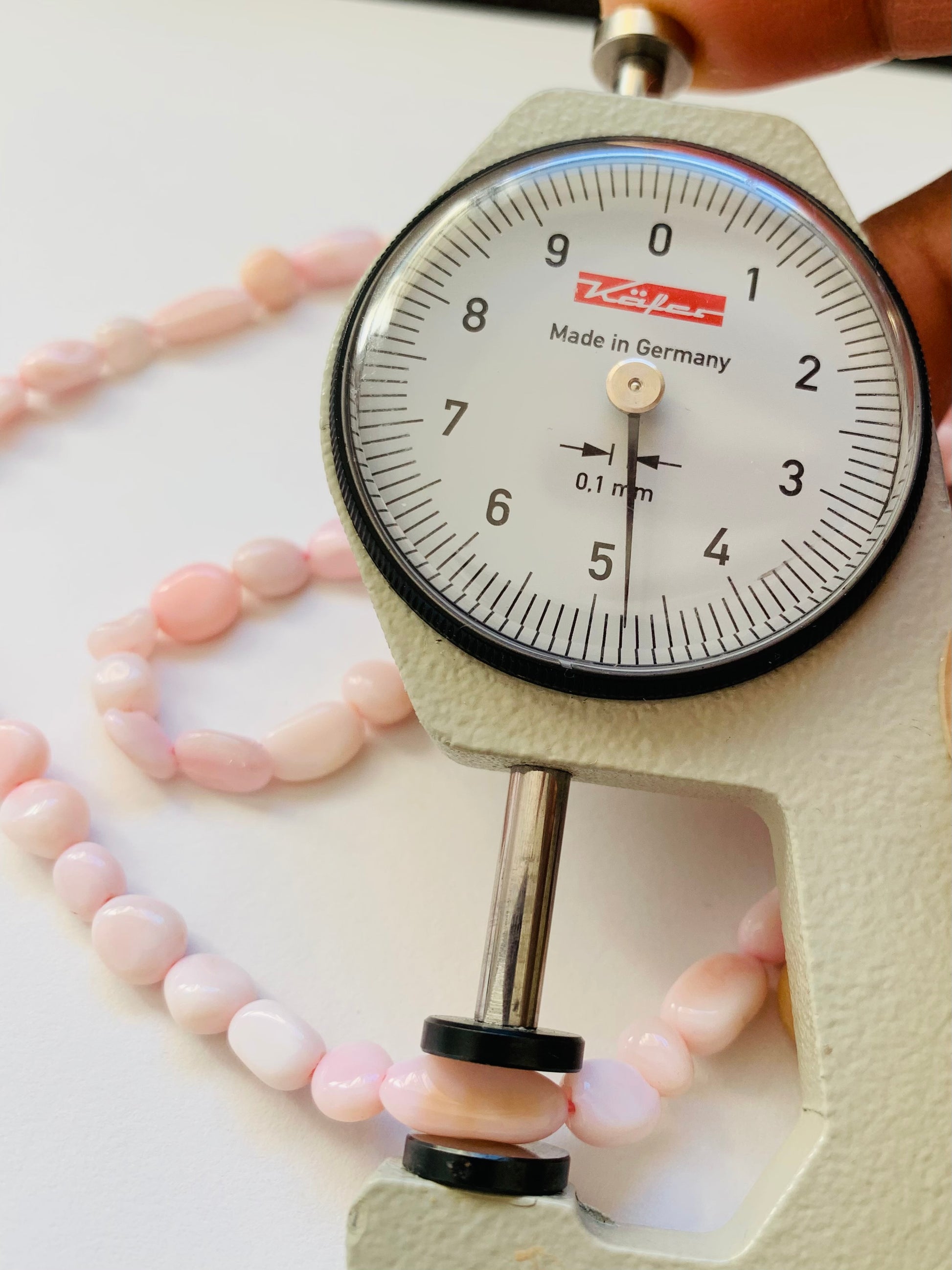 Detailed view of a measuring dial gauge and gemstone bead, emphasising the dimensions for crafting Opal gemstone beads.