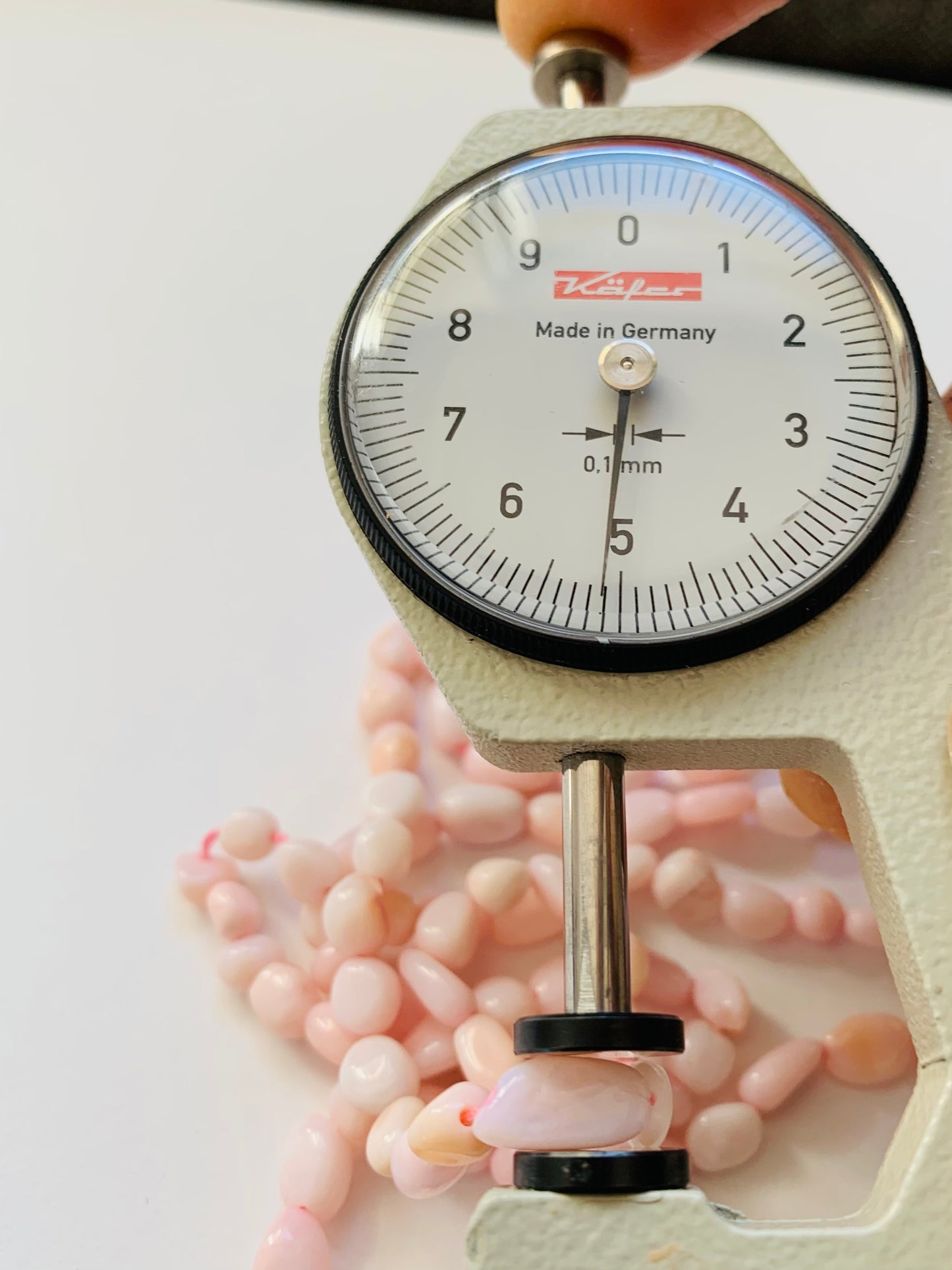 Close-up of a measuring dial gauge tool alongside a string, highlighting the precision of measurements for Opal jewellery.