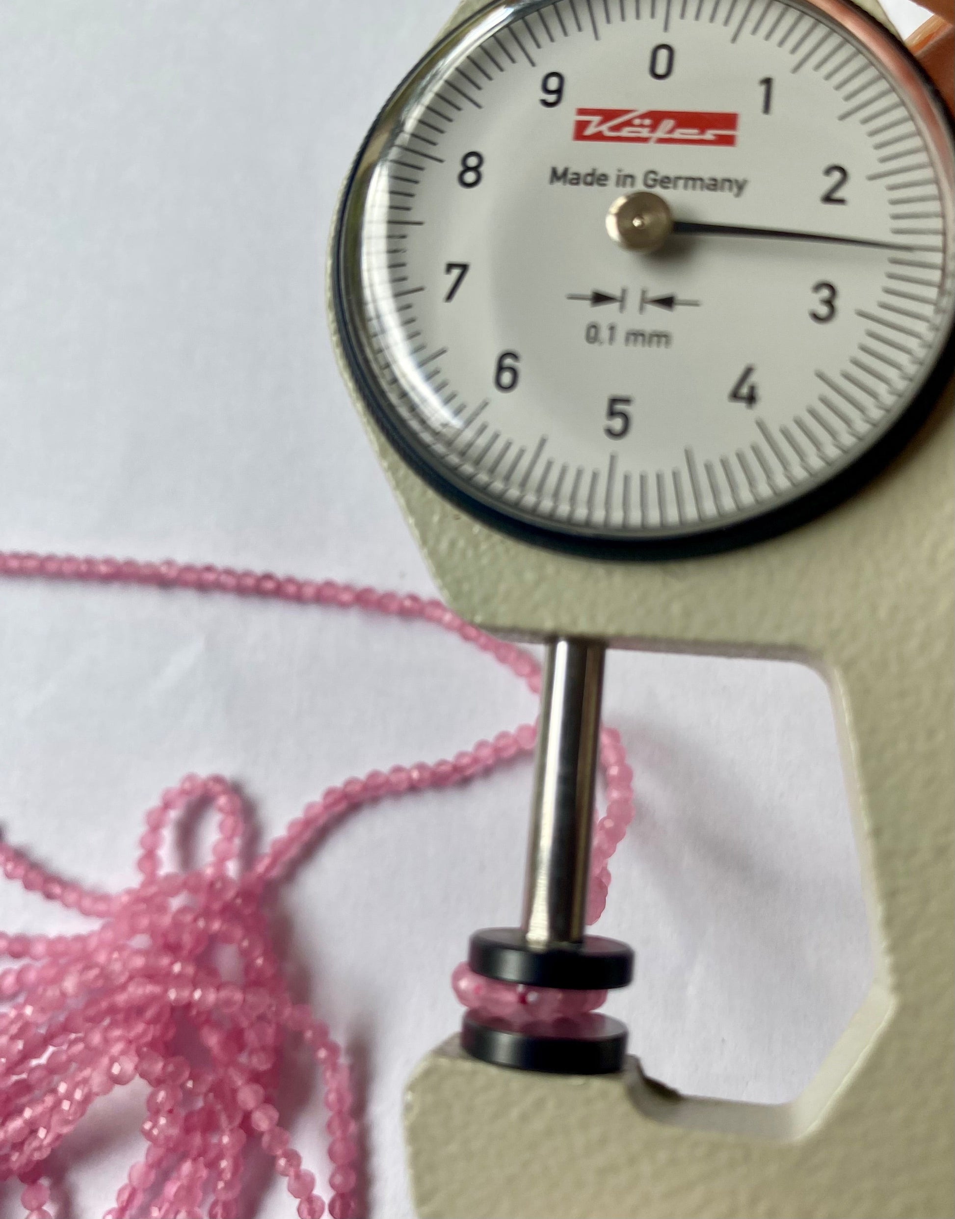 A dial gauge measures the Pink Quartz Faceted Rondelle 2.5mm gemstone.