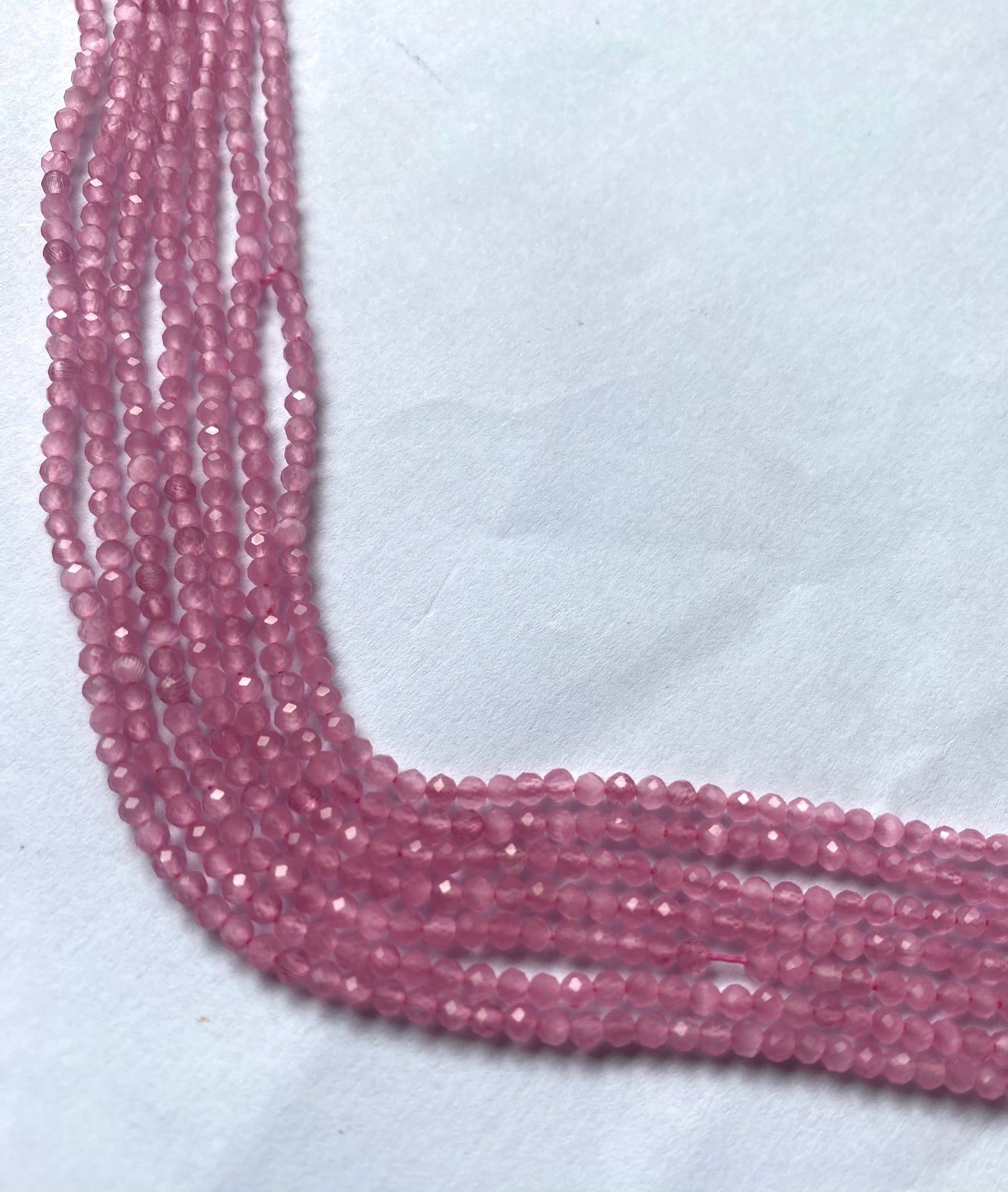 A close-up of a strands of faceted quartz beads, measuring 2.5mm, highlighting their rich, vibrant hue.  