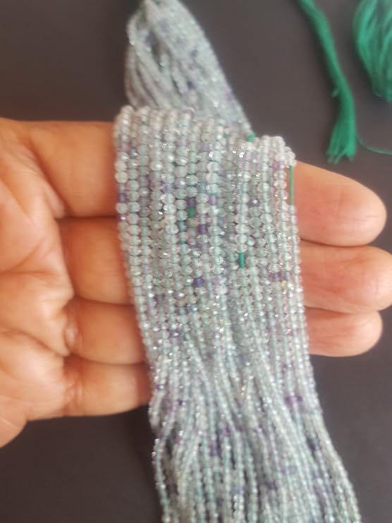 A person holding a strands of green and purple Prehnite faceted rondelle beads, showcasing their natural beauty and shine.