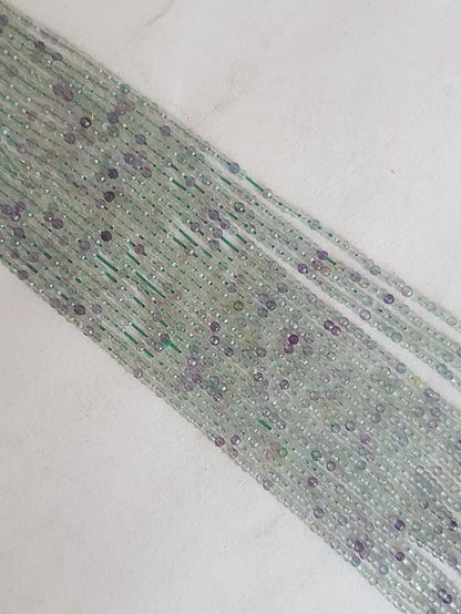 Strands of 2mm prehnite beads, showcasing a mix of green and purple faceted rondelles, ideal for crafting and design.
