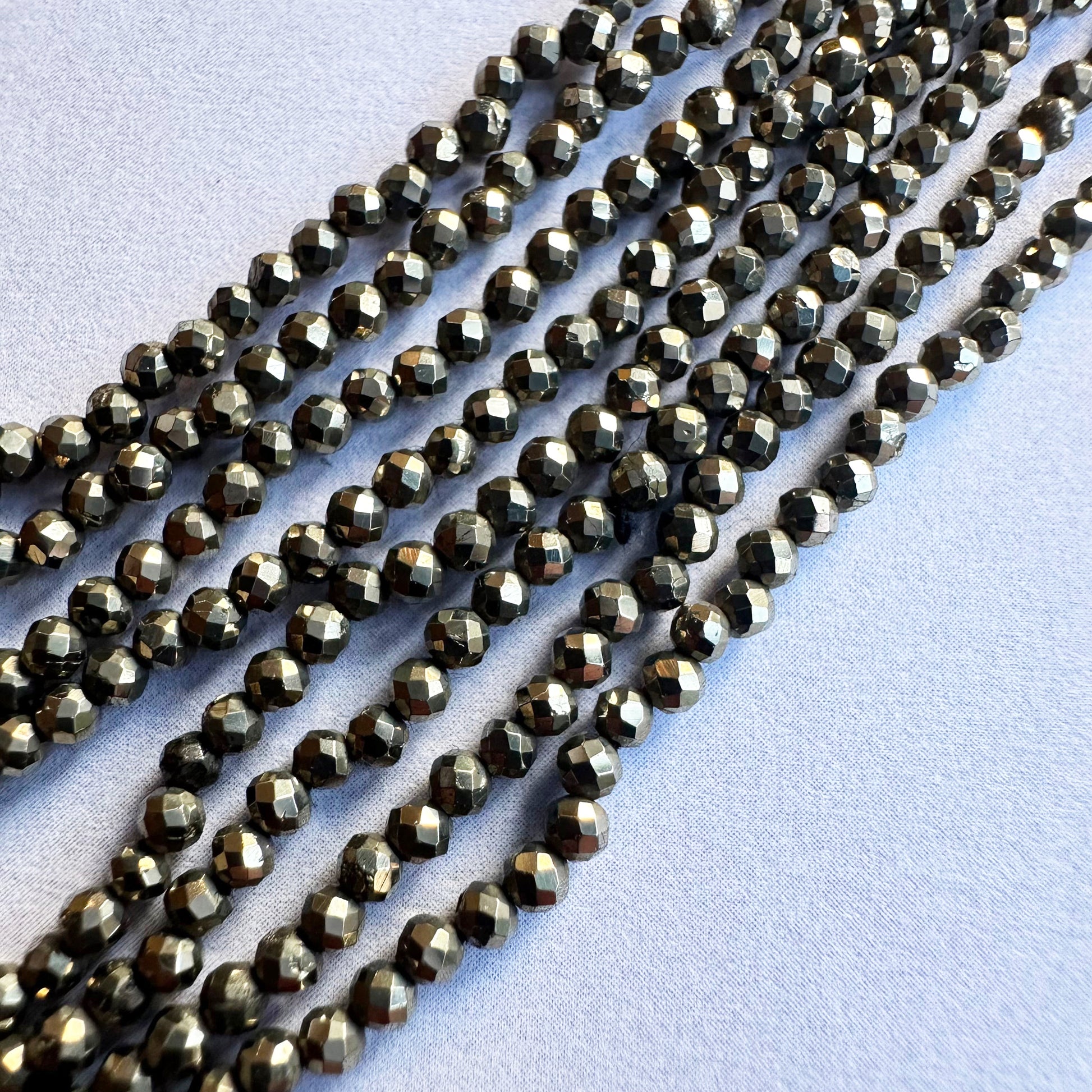 Strands of 2.1mm Pyrite faceted rondelle beads display exceptional clarity and uniform cutting.