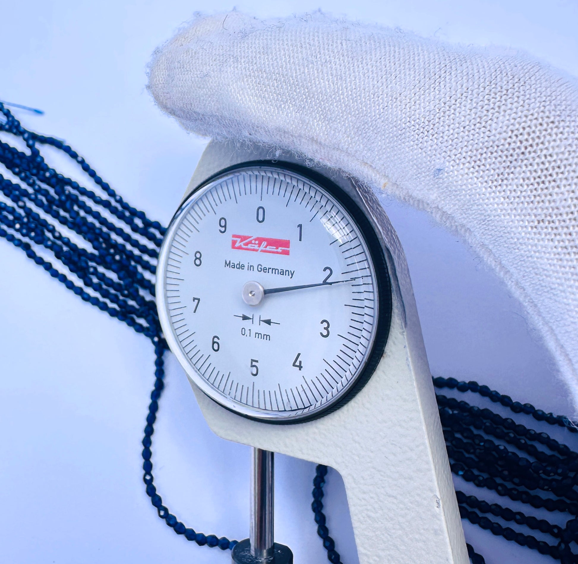 A dial gauge measures the Quartz faceted rondelle 2.2mm gemstone.