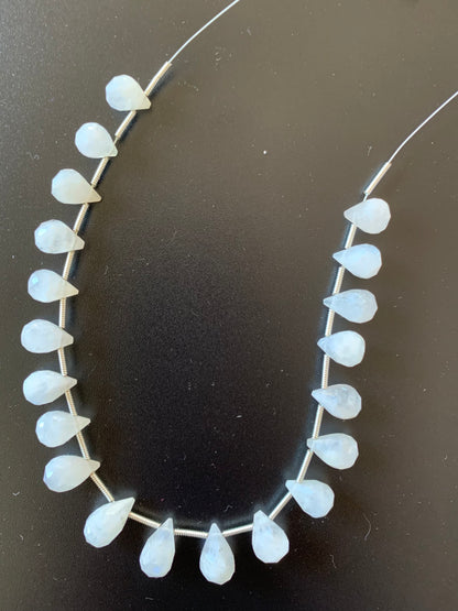 Elegant moonstone beads are arranged on a black surface, their soft colour and shine creating a captivating display.