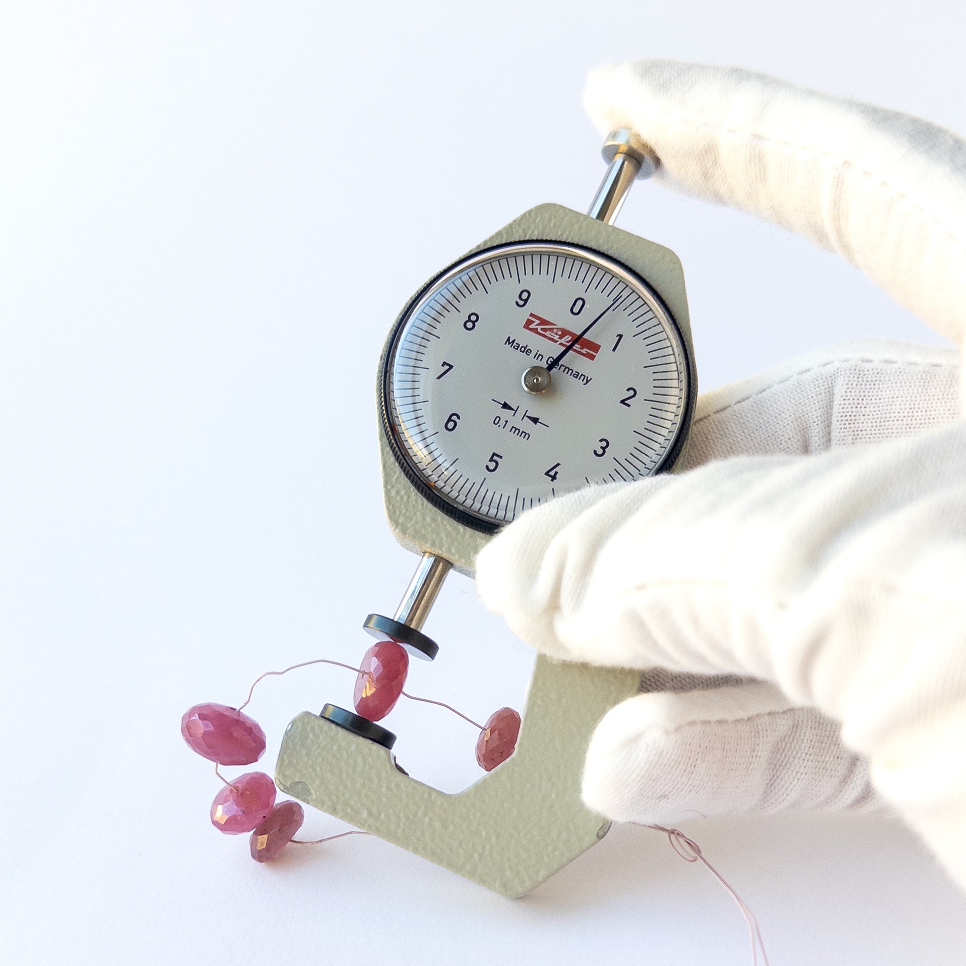 A dial gauge measures the Ruby faceted rondelle 8.5–10.7mm gemstone.