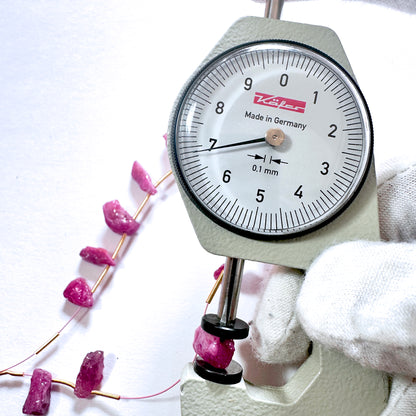 A dial gauge measures the ruby rough side drilled 7mm gemstone for accuracy and quality.