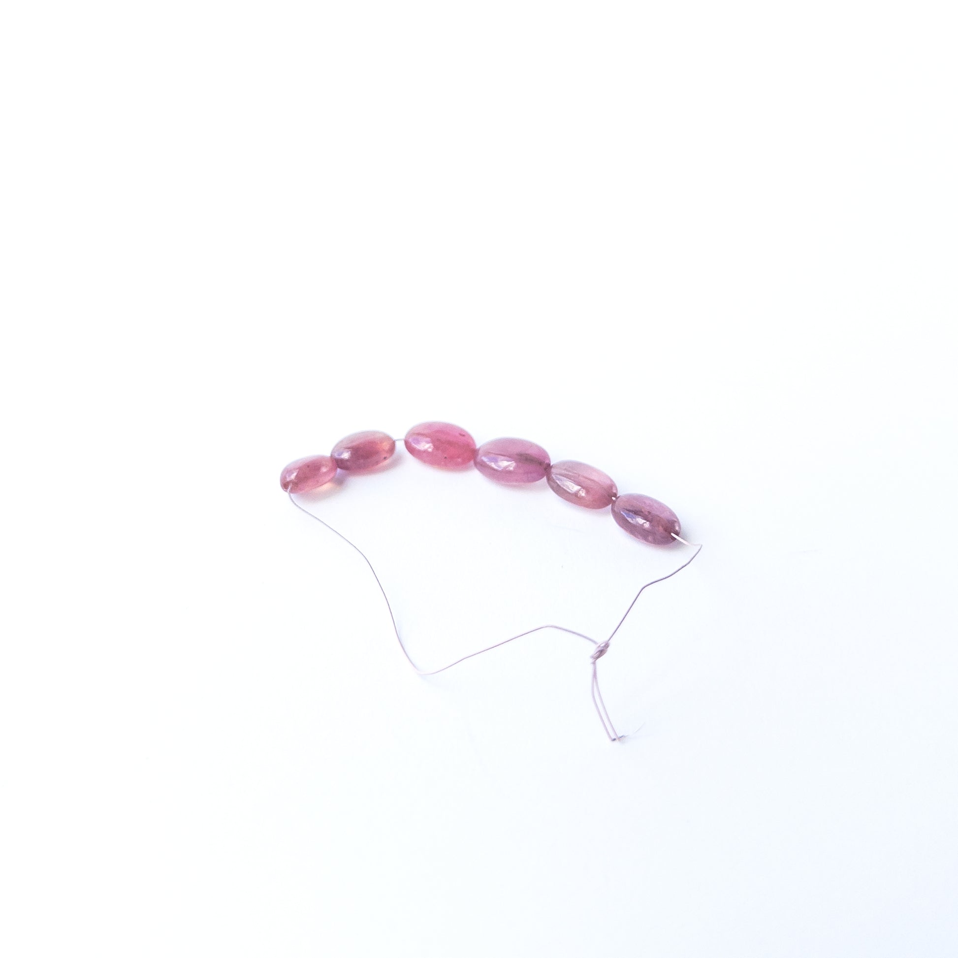 Authentic Ruby oval beads showcasing polished shine and vibrant crimson tones.