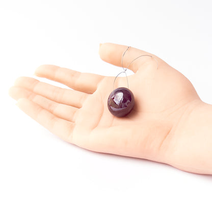 A person holds delicate pieces of Ruby beads, showcasing their smooth rondelle design.