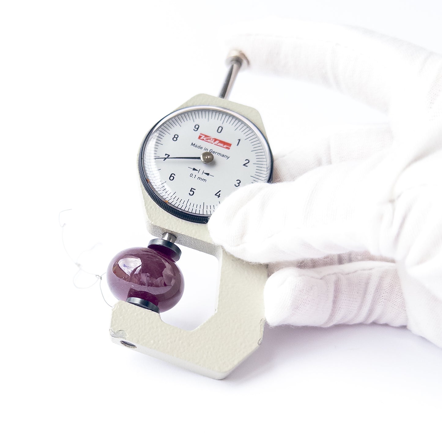 A dial gauge measures the Ruby smooth rondelle 23mm gemstone.