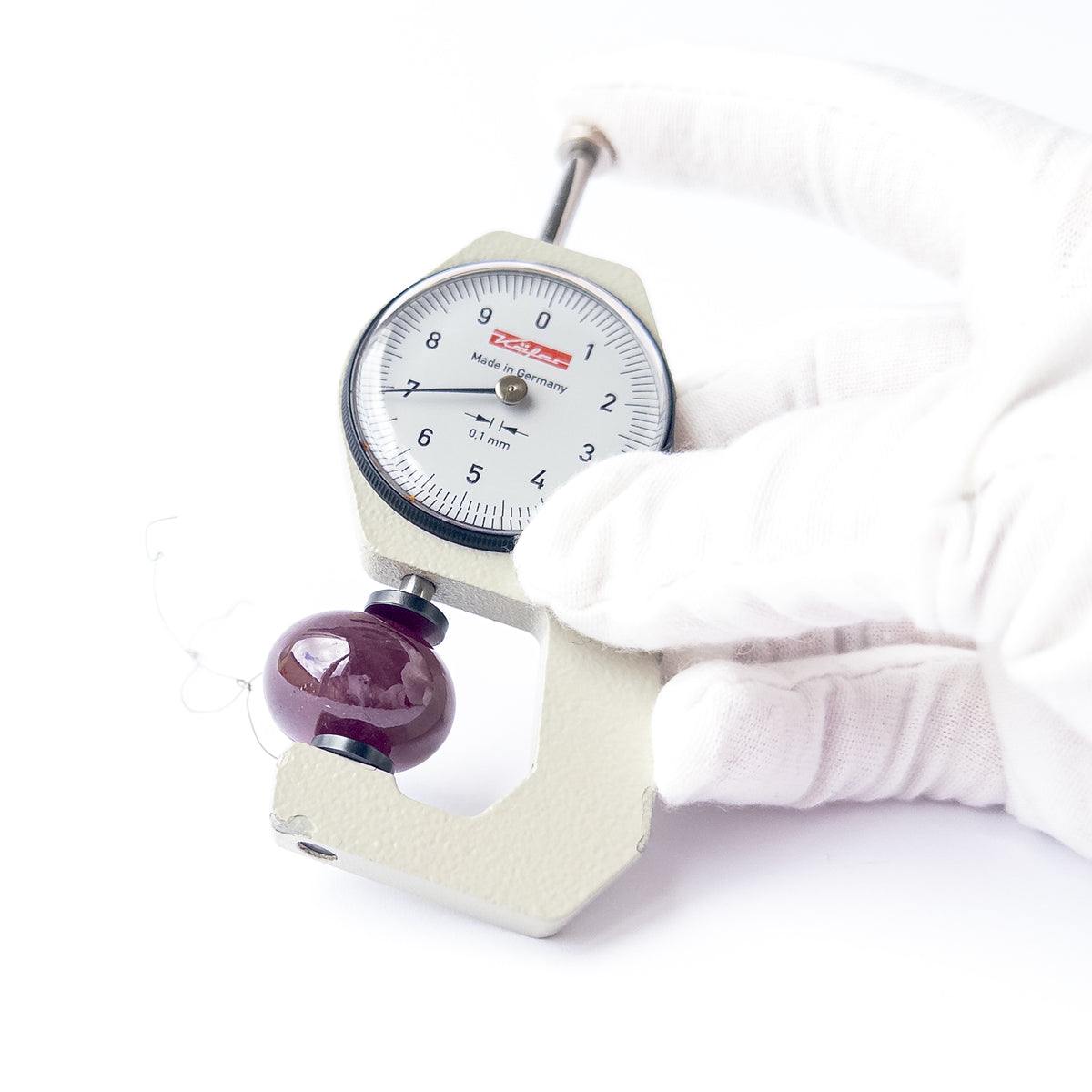 A dial gauge measures the Ruby smooth rondelle 23mm gemstone.