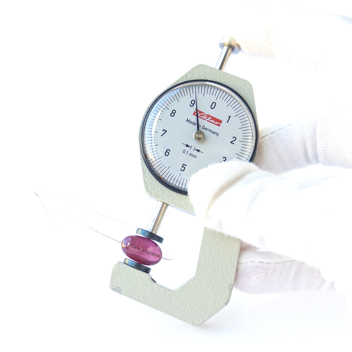 A dial gauge measures the Ruby smooth tumble 15.2 × 9.2mm gemstone.