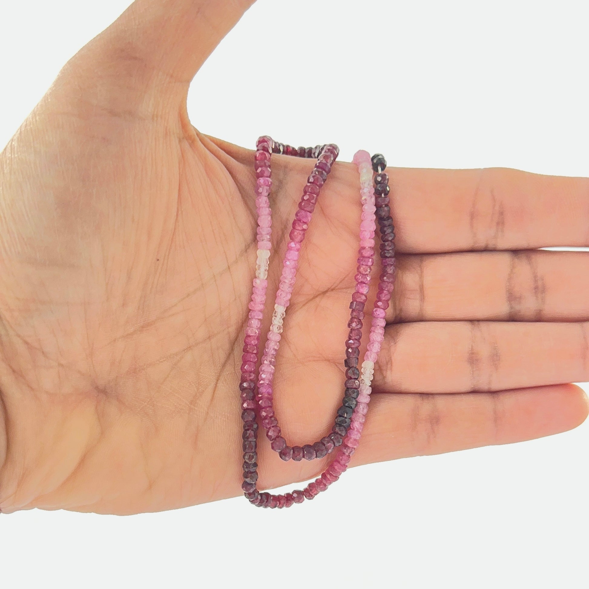 Ruby shaded rondelle beads held in hand for scale