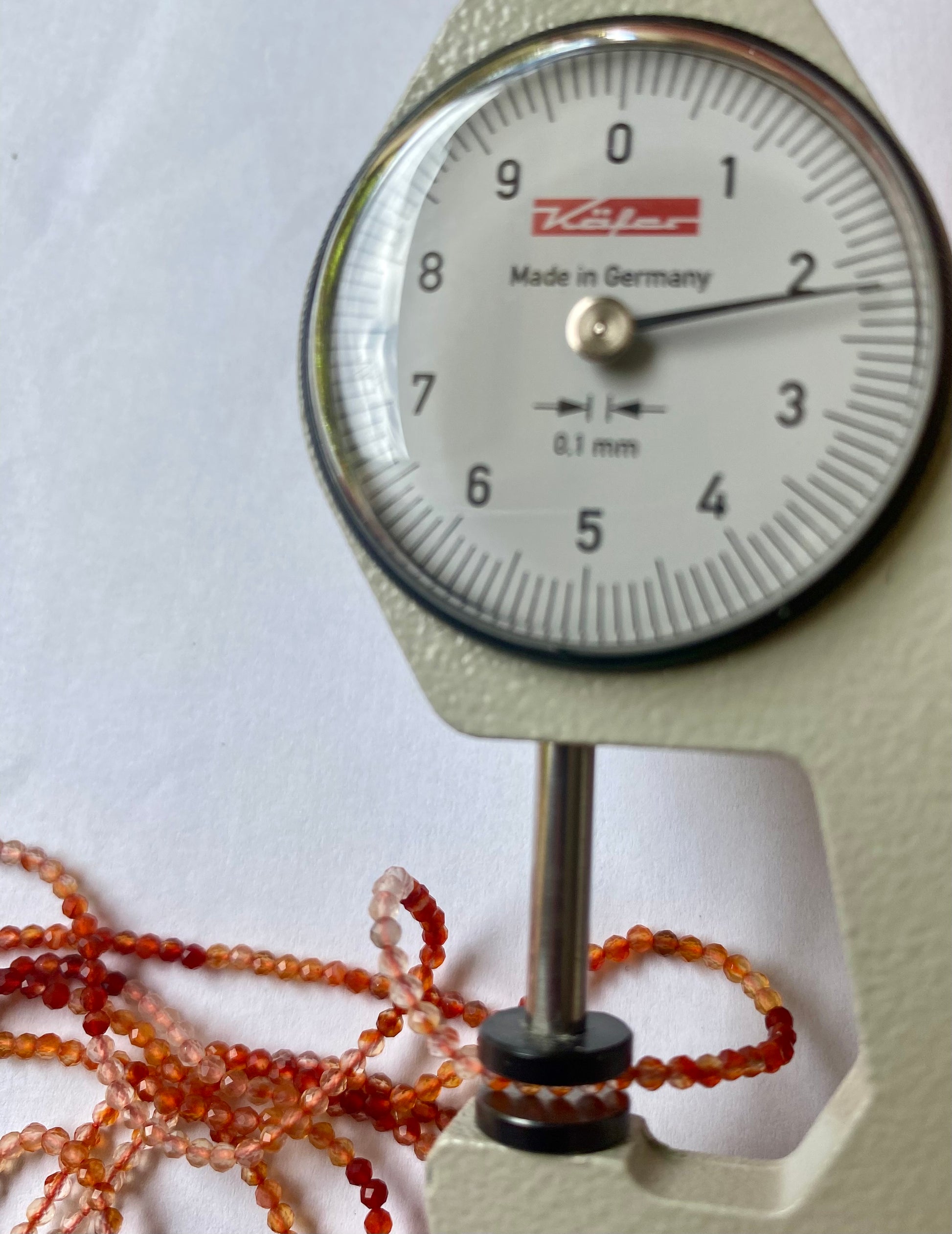 Close-up view of a dial gauge  with shaded carnelian beads, measuring between 2.2mm.