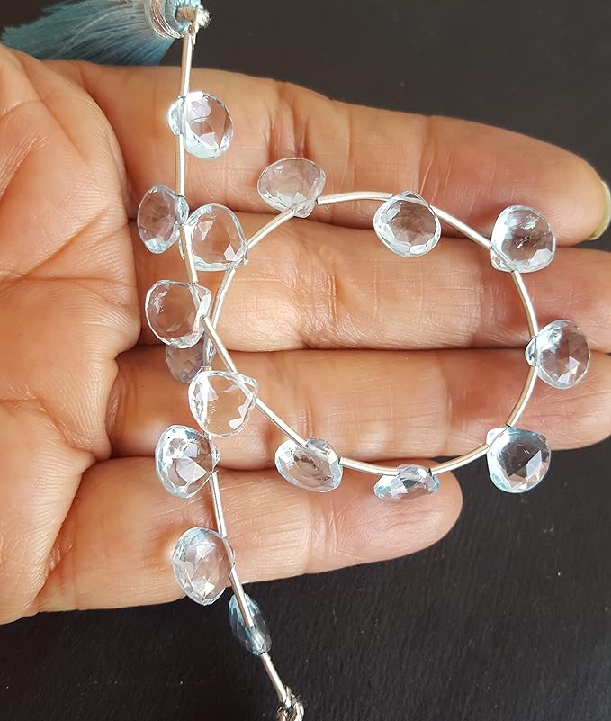 Close-up of a person holding a elegant gemstone strand made with sky blue topaz, showcasing its vibrant design.
